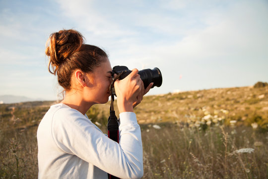 Female photographer, taking pictures of mountain landscape at sunset in outdoors