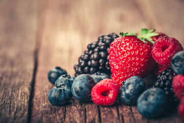Fresh Summer Berries mix with Strawberry, Raspberry, Red currant, Blueberry and Blackberry on wood background.