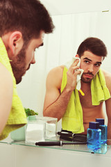 bearded handsome man washing face and cleaning with towel in bathroom, every day routine 