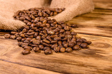 Sackcloth and scattered coffee beans on wooden table
