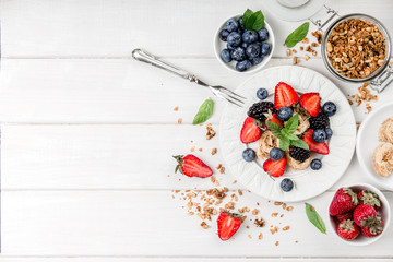 Healthy breakfast with granola, fruits, berries on white background.