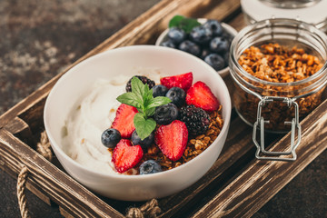 Healthy breakfast with granola, yogurt, fruits, berries on dark metal background. Summer homemade...