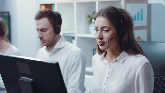 Portrait smiling young woman look at camera service operator taking calls in busy call center office business worker computer corporate headset job man service group finance phone slow motion