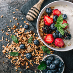 Healthy breakfast with granola, yogurt, fruits, berries on dark metal background. Summer homemade breakfast.