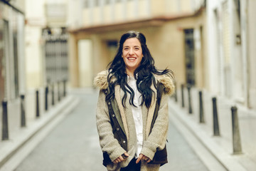 Middle-aged woman smiling and laughing happily walking through the city.