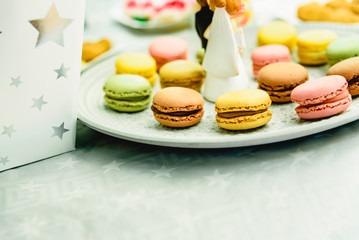 Dessert at a wedding, with figures of newly-married dolls, on a plate with macarons.