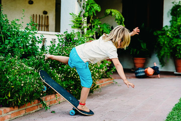 5 year old boy practicing skate in his backyard, stumbling and falling to the ground. © Road Red Runner