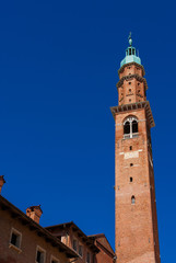 Fototapeta na wymiar Bissara Tower rises above historic center tradtional red tile roofs and old chimney. Completed in the 15th century, it's the tallest building in Vicenza (with copy space)