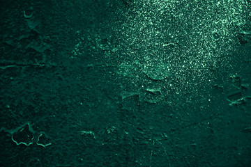 Vintage green background. Rough painted wall of emerald color. Imperfect plane of virid colored. Uneven old decorative toned backdrop of green tint. Texture of emerald hue. Ornamental stony surface.