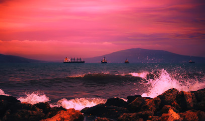 Red sunset over the black sea, mountains, purple sky. Summer sea scenic landscape in stormy evening