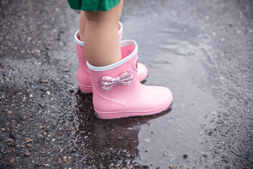 水溜まりに女の子が長靴を履いて水で遊んでいる