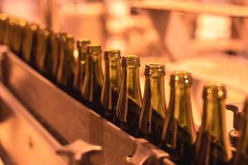 View of glass bottles on the conveyor belt, bottle necks on the production line, brewery equipment, inside wine factory, process of alcohol liquor manufacture production