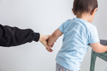 白背景に赤ちゃんの腕を女性の手で引張ている教育子育て虐待