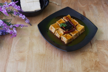 Fried tofu in black dish on wooden background