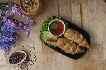 Fried tofu with sauce on dish and wooden background.