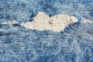 Denim texture.Blue jeans with threads and holes for the background