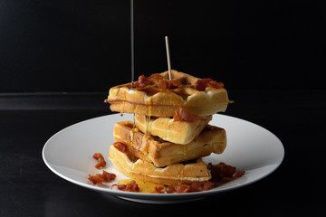 pouring maple syrup on the cheese belgian waffles with bacon