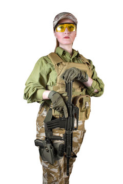 Beautiful fully equipped military soldier woman in protective armor tactical vest, camouflage pants, gloves, cap and glasses holding an automatic rifle M16, isolated photo.