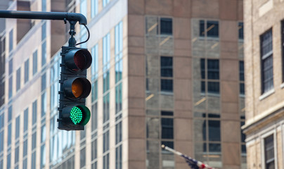 Green traffic lights for cars, blur office buildings background