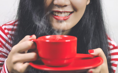 Asian women holding a red cup of coffee.