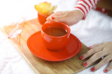 The woman's hand holding a red cup of coffee