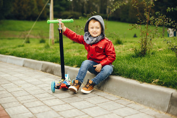 Cute little boy in a park. Child playing with a skate.