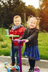 Two cute kids in a park. Children playing with a skate