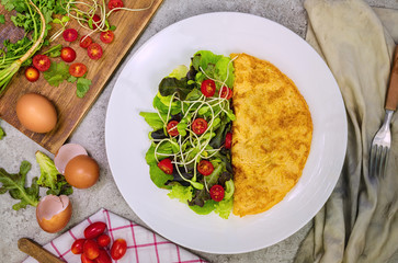 Omelette and vegetable salad in a white ceramic dish
