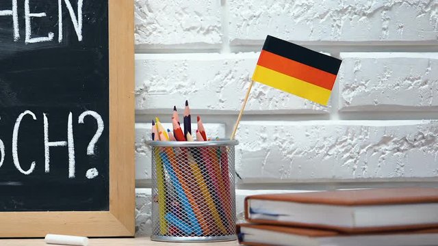 Do you speak German on blackboard, national flag in pen cup, learning language