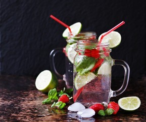 lemonade with strawberries, basil, lime  in a jar with a handle. dark background. Soft focus