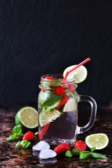 lemonade with strawberries, basil, lime  in a jar with a handle. dark background. Soft focus