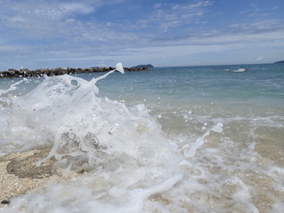 Closeup with splashing silky smooth swash water over a single rock into the seashore in Kota...