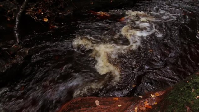 Scottish river creek flowing in slow motion in the fall autumn season at finnich glen devils pulpit in the united kingdom