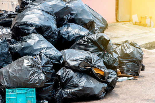pile of  black garbage bags at city street, waste management in large cities