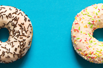 Fresh glazed donuts with chocolate and colorful sprinkles on a orange background.