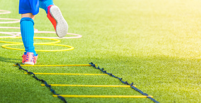 Child Feet With Soccer Boots Training On Agility Speed Ladder In Soccer Training.