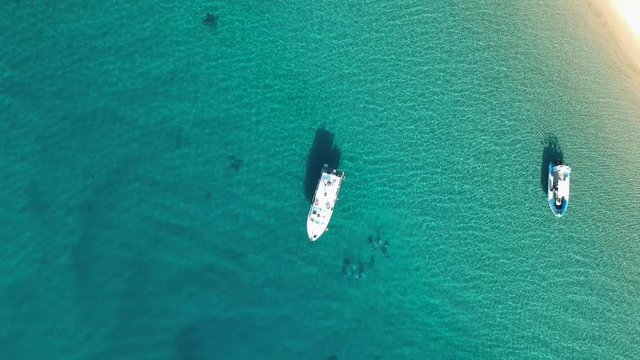 Aerial footage of scuba divers underwater next to two charter boats