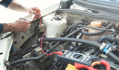 Mechanic with a multimeter testing car engine. Car service