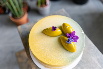 Mousse dessert covered with yellow velour. Modern european cake. Sweet dessert and tea party. French cuisine. Flowers theme. Copy space