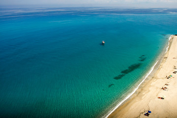 Turquoise water with boat and a line of sandy beach, background wallpapers. 