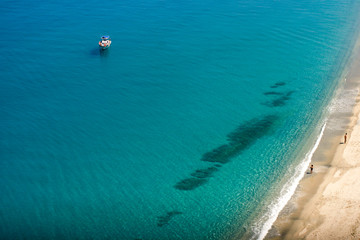 Turquoise water with boat and a line of sandy beach, background wallpapers. 