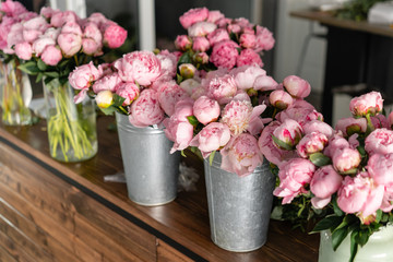 The counter of the flower shop. Pink peonies in a metal vase. Beautiful peony flower for catalog or online store. Floral shop concept . Beautiful fresh cut bouquet. Flowers delivery