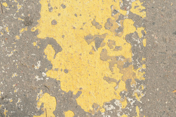 Old asphalt surface with yellow paint on it close up. Abstract background	