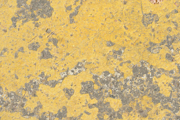 Old asphalt surface with yellow paint on it close up. Abstract background