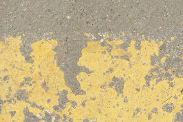 Old asphalt surface with yellow paint on it close up. Abstract background