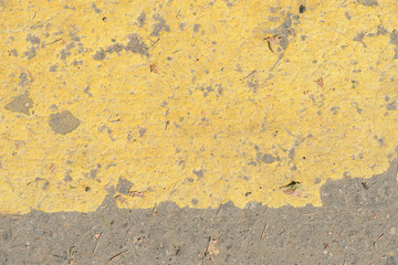 Old asphalt surface with yellow paint on it close up. Abstract background
