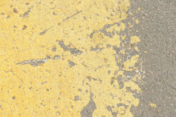 Old asphalt surface with yellow paint on it close up. Abstract background