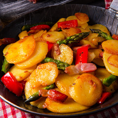 Fried potatoes with smoked bacon, green asparagus and paprika.