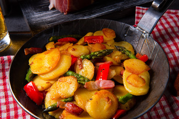 Fried potatoes with smoked bacon, green asparagus and paprika.