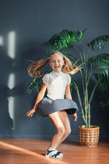 Blonde girl in dress jumping in modern room with swing.
